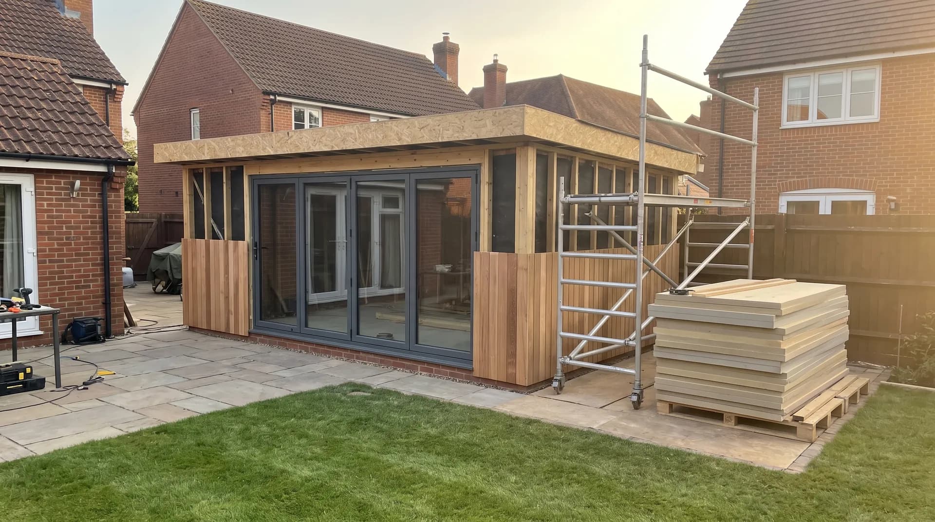 Timber-frame garden room under construction in Wokingham showing fresh brickwork and stacked cement bags on site