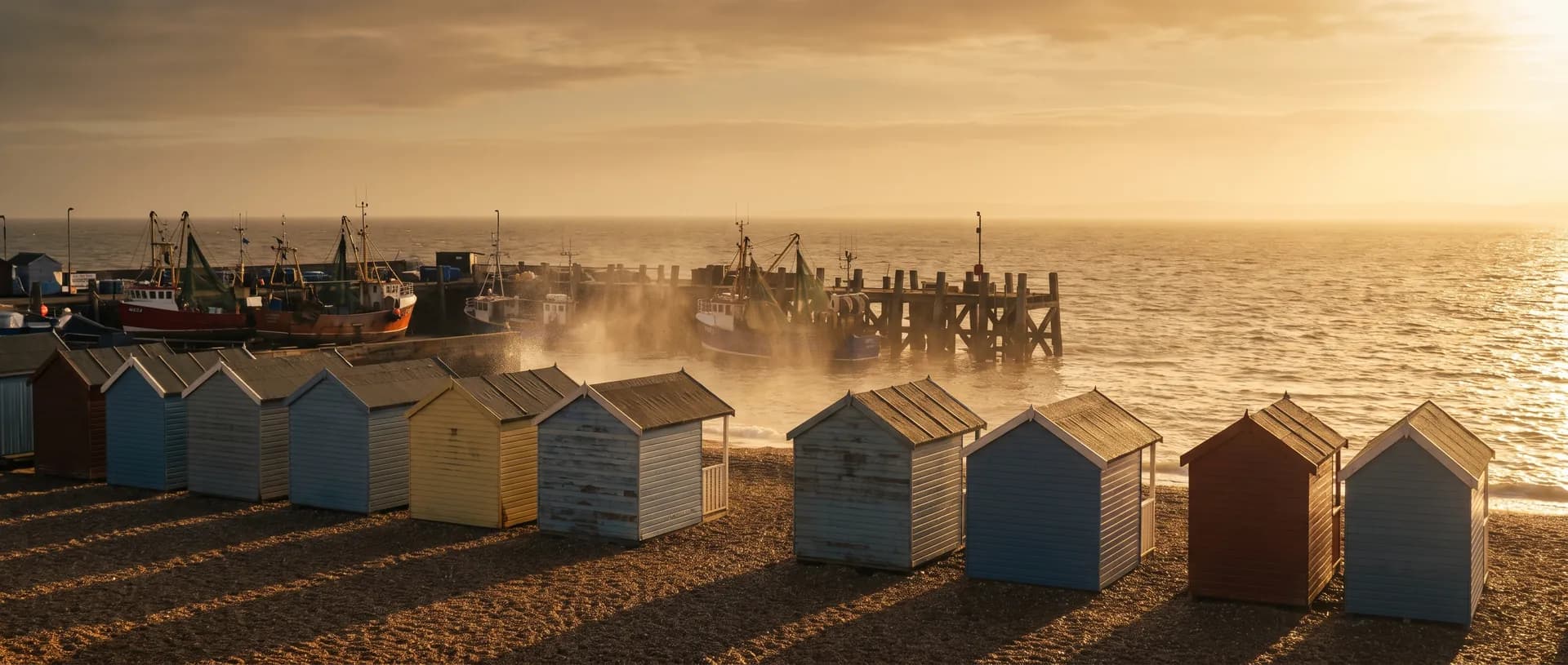 Whitstable harbour and beach huts at golden hour, near Faversham, Kent